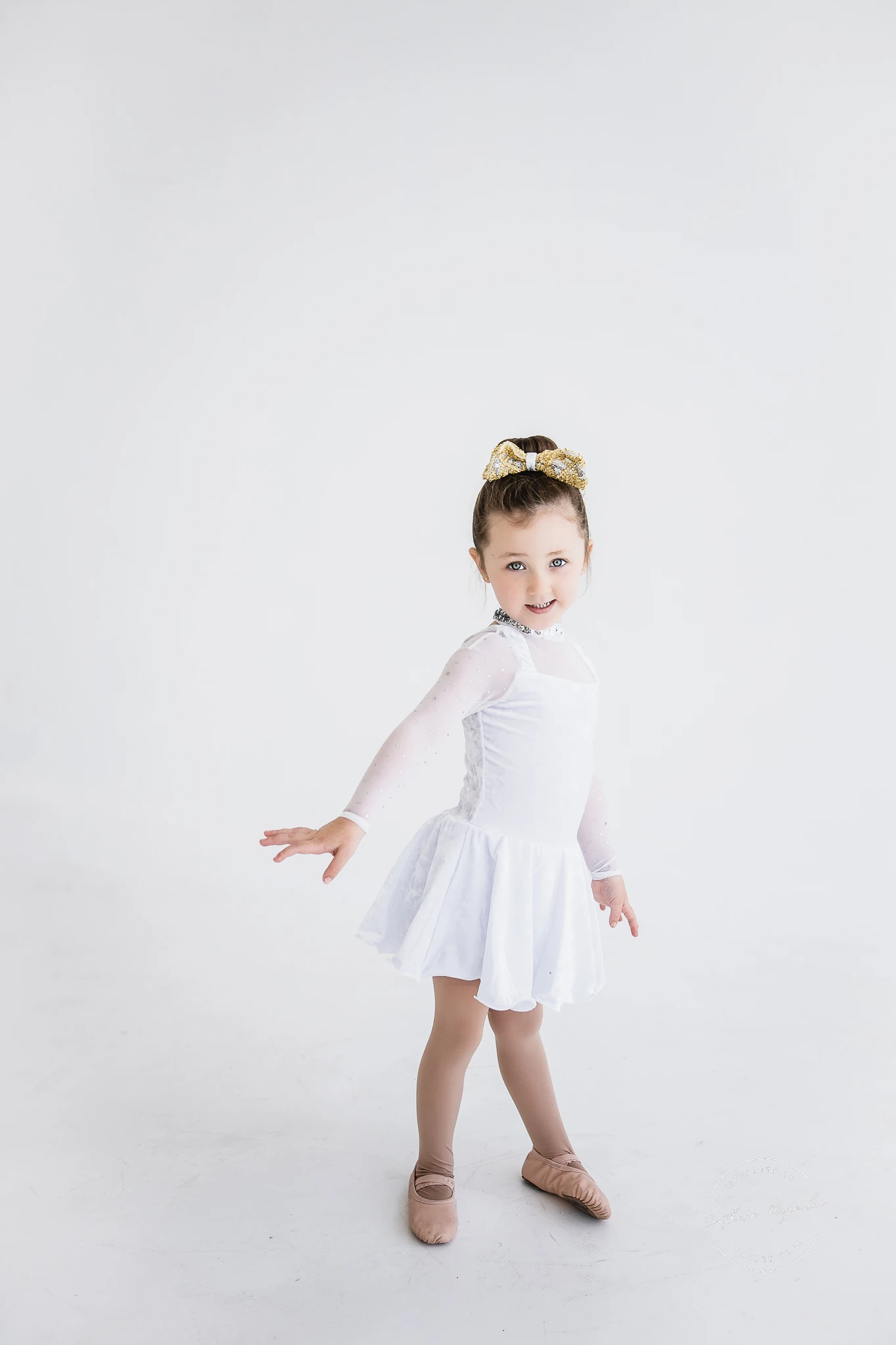 A young dancer in a white ballet dress and slippers during a portrait session