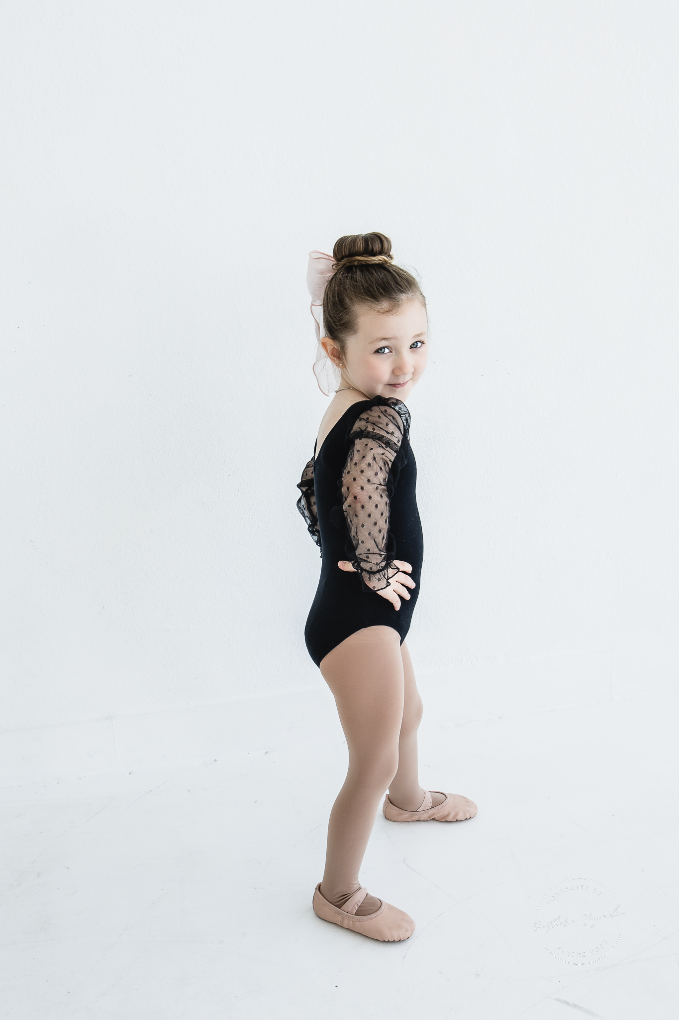 A young dancer in a black leotard posing during a studio photo session
